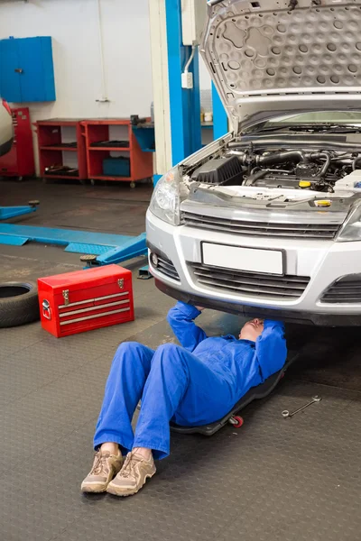 Mecánico mintiendo y mirando debajo del coche — Foto de Stock