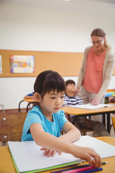 かわいい生徒を教室の机で書く — ストック写真