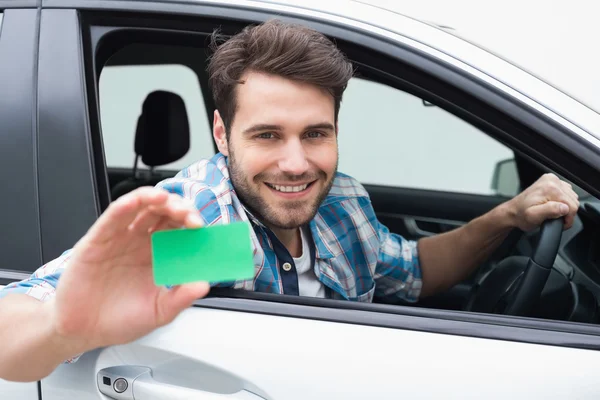 Young man smiling and holding card — Stock Photo, Image