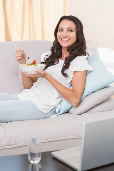 Brunetka jedzenie sałatka na kanapie — Zdjęcie stockowe