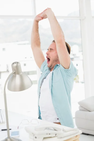 Smiling businessman stretching at desk — Stock Photo, Image