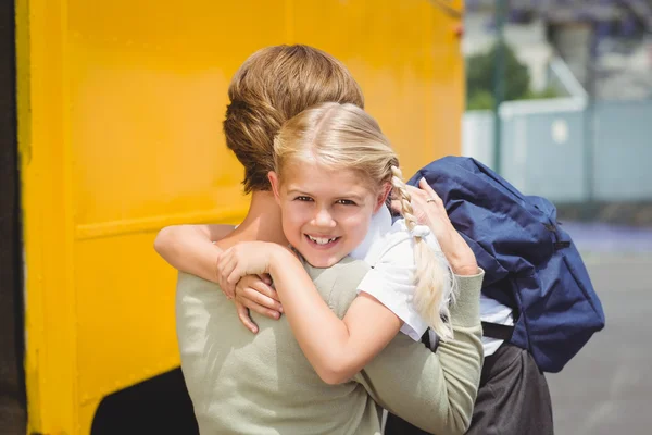 Mother hugging her daughter by school bus — Stock Photo, Image