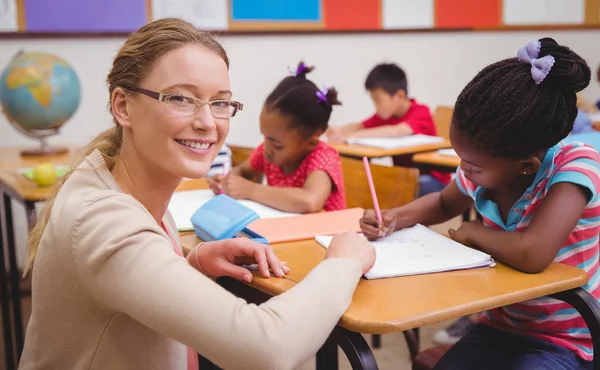 可爱的学生坐在教室里的桌子上写 — 图库照片