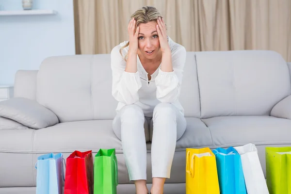 Blonde op Bank in de buurt van shopping tassen — Stockfoto