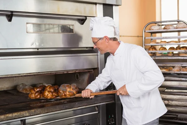 Focused baker taking out fresh loaf — Stock Photo, Image