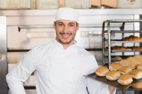 Zufriedener Bäcker zeigt Tablett mit frischem Brot — Stockfoto