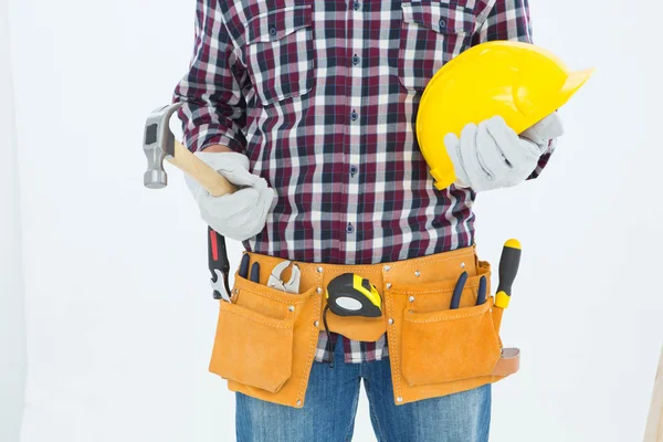 Handyman holding hard hat and hammer — Stock Photo, Image