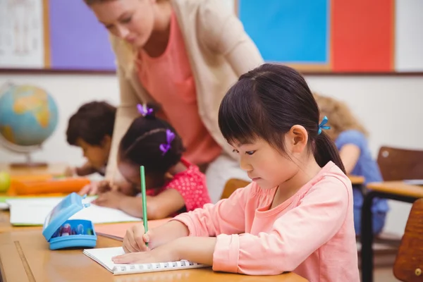 Schattig leerlingen schrijven op Bureau in klas — Stockfoto