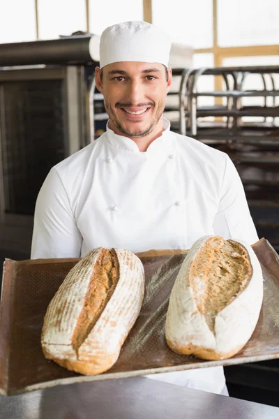 Happy baker showing tray of fresh bread — Stock Photo, Image