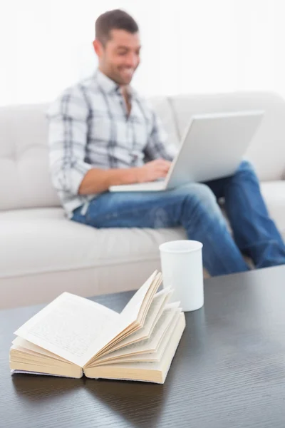 Человек пишет на компьютере, сидя на диване — стоковое фото