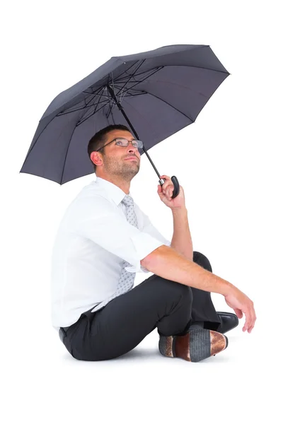 Geschäftsmann sitzt mit schwarzem Regenschirm auf dem Boden — Stockfoto