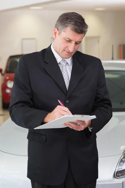 Hombre de negocios serio escribiendo en el portapapeles — Foto de Stock