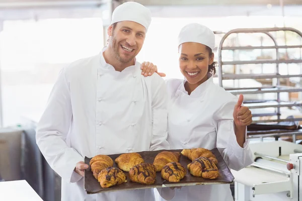 Panaderos sonriendo con bandejas de croissants —  Fotos de Stock
