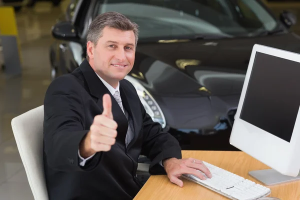 Businessman giving thumbs up at desk — Stock Photo, Image