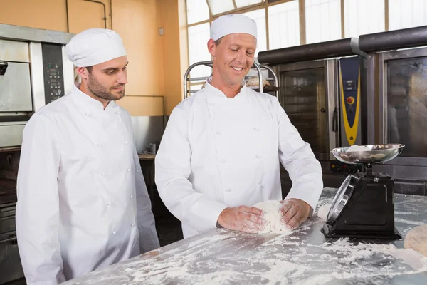 Baker looking his colleague kneading dough — Stock Photo, Image
