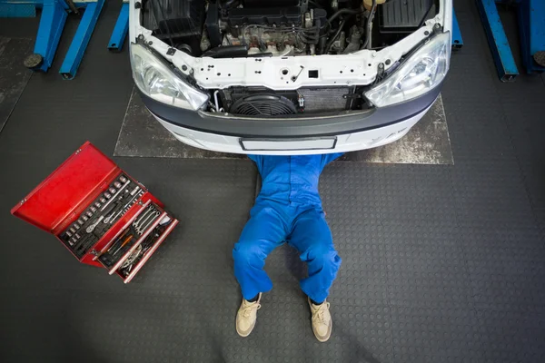 Mecánico mintiendo y trabajando bajo el coche — Foto de Stock