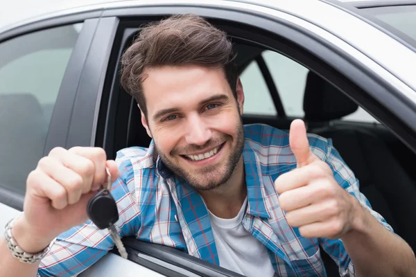 Jovem sorrindo para a câmera mostrando a chave — Fotografia de Stock