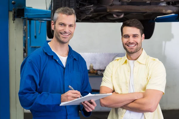 Kunde und Mechaniker lächeln in die Kamera — Stockfoto