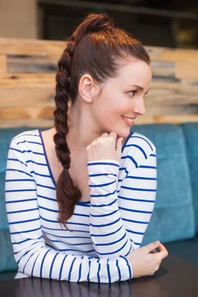 Mladá žena se usmívá na stůl — Stock fotografie