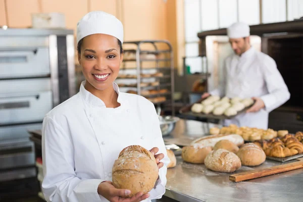 Pretty baker at camera with loaf — Stock Photo, Image