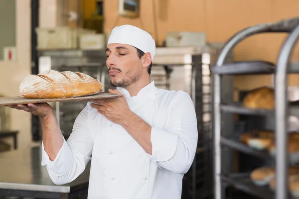 Baker smelling a freshly baked loaf — Stock Photo, Image