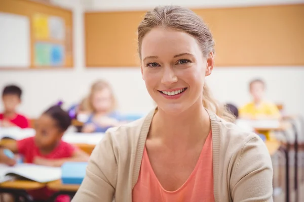 Pretty teacher smiling at camera at top of classroom Royalty Free Stock Images