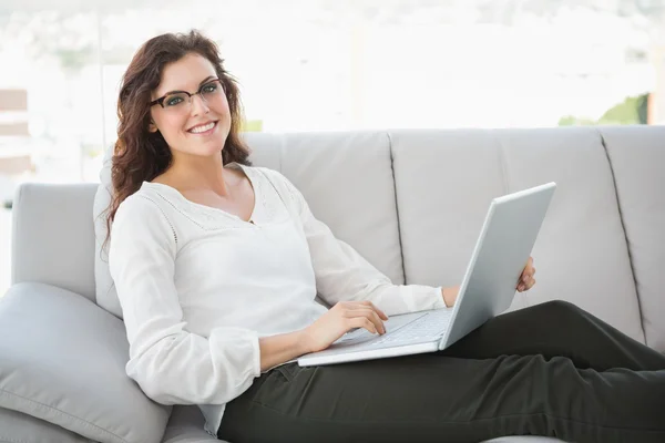 Businesswoman sitting on sofa using laptop Stock Picture