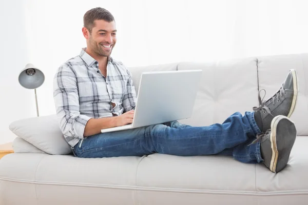 Relaxing man on a sofa with a laptop Royalty Free Stock Images