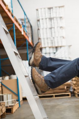 Worker falling off ladder in warehouse clipart