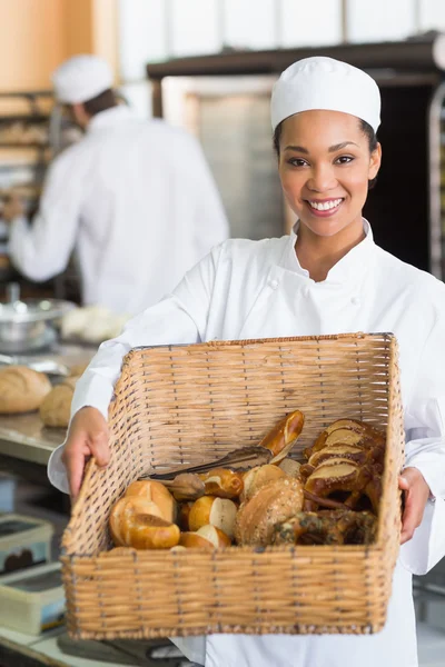 Pretty baker showing basket of bread — Stock Photo, Image