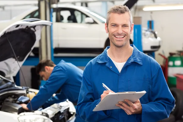 Lachende mechanic schrijven op Klembord — Stockfoto