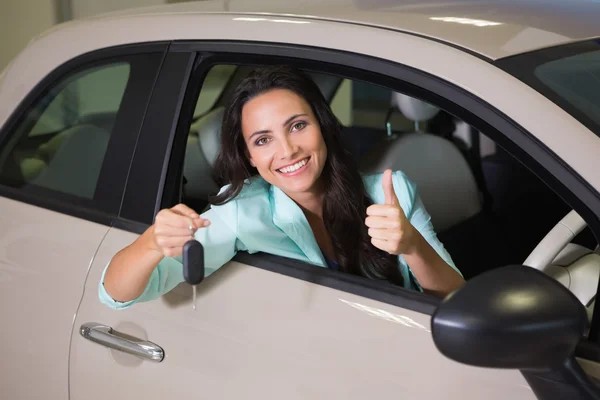 Lachende vrouw auto toets ingedrukt te houden terwijl het geven van duimen omhoog — Stockfoto