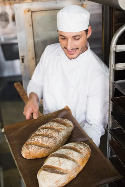 Happy baker holding tray of fresh bread — Stock Photo, Image