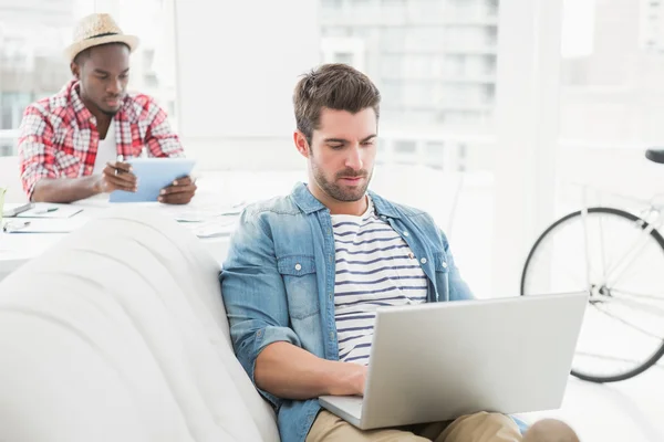 Homem de negócios concentrado usando laptop no sofá — Fotografia de Stock