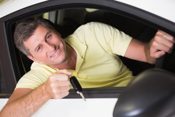 Un uomo sorridente che tiene in mano la chiave di una macchina seduto in macchina — Foto Stock