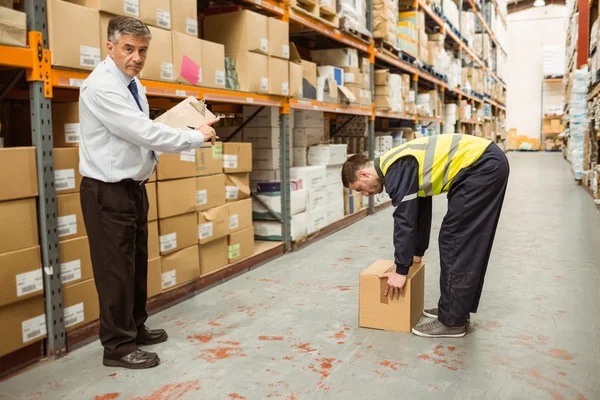 Gerente assistindo trabalhadores transportando caixas — Fotografia de Stock