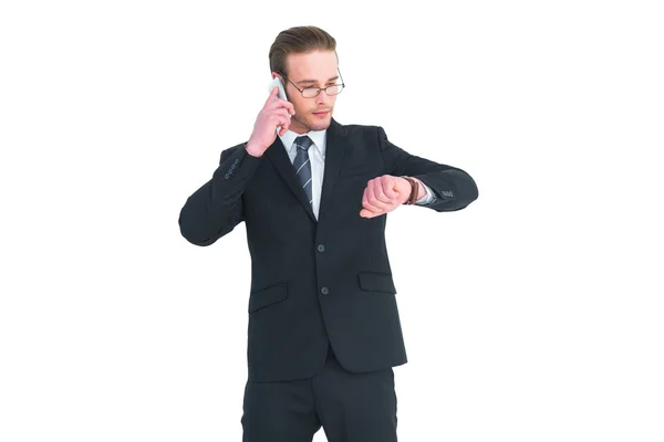 Serious businessman phoning while checking time — Stock Photo, Image