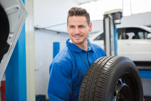 Mechaniker hält ein Reifenrad — Stockfoto