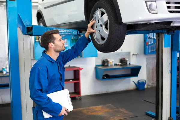 Mechanic looking at car tires — Stock Photo, Image