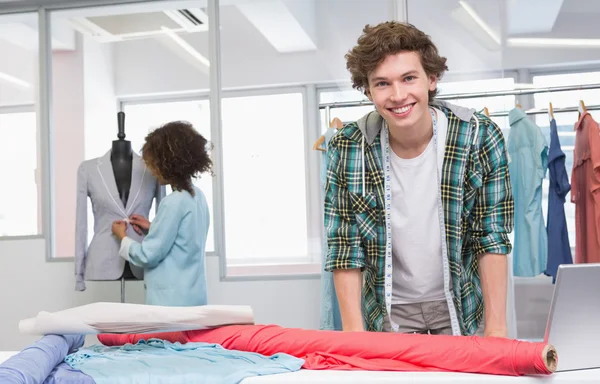 Smiling students working with fabric and model — Stock Photo, Image