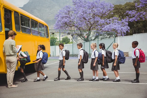 Söta skolbarn väntar på att få på skolbussen — Stockfoto