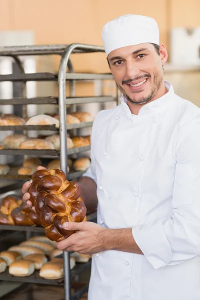 Smiling baker holding fresh loaves — Stock Photo, Image