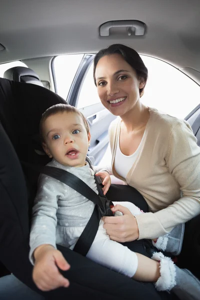 Mère sécurisant son bébé dans le siège auto — Photo