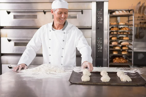 Baker putting dough on baking tray — Stock Photo, Image