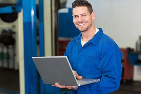 Lachende mechanic met behulp van zijn laptop — Stockfoto