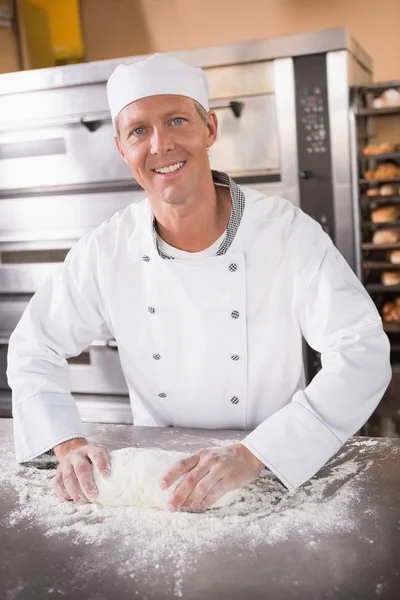 Smiling baker kneading dough on counter — Stock Photo, Image