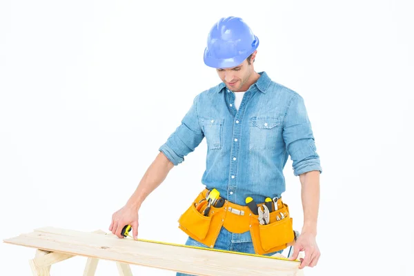 Carpintero midiendo tablón de madera — Foto de Stock