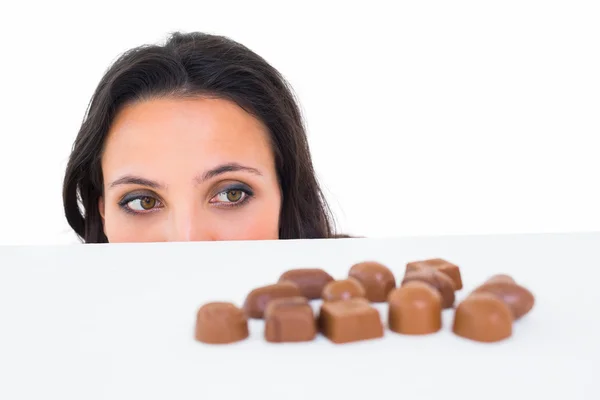 Schön brünette peeking bei schokolade — Stockfoto