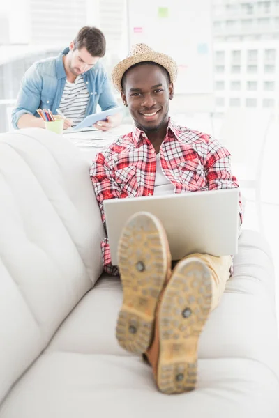 Cheerful businessman using laptop on couch — Stock Photo, Image