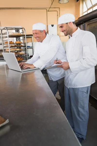 Panaderos trabajando juntos en el ordenador portátil — Foto de Stock